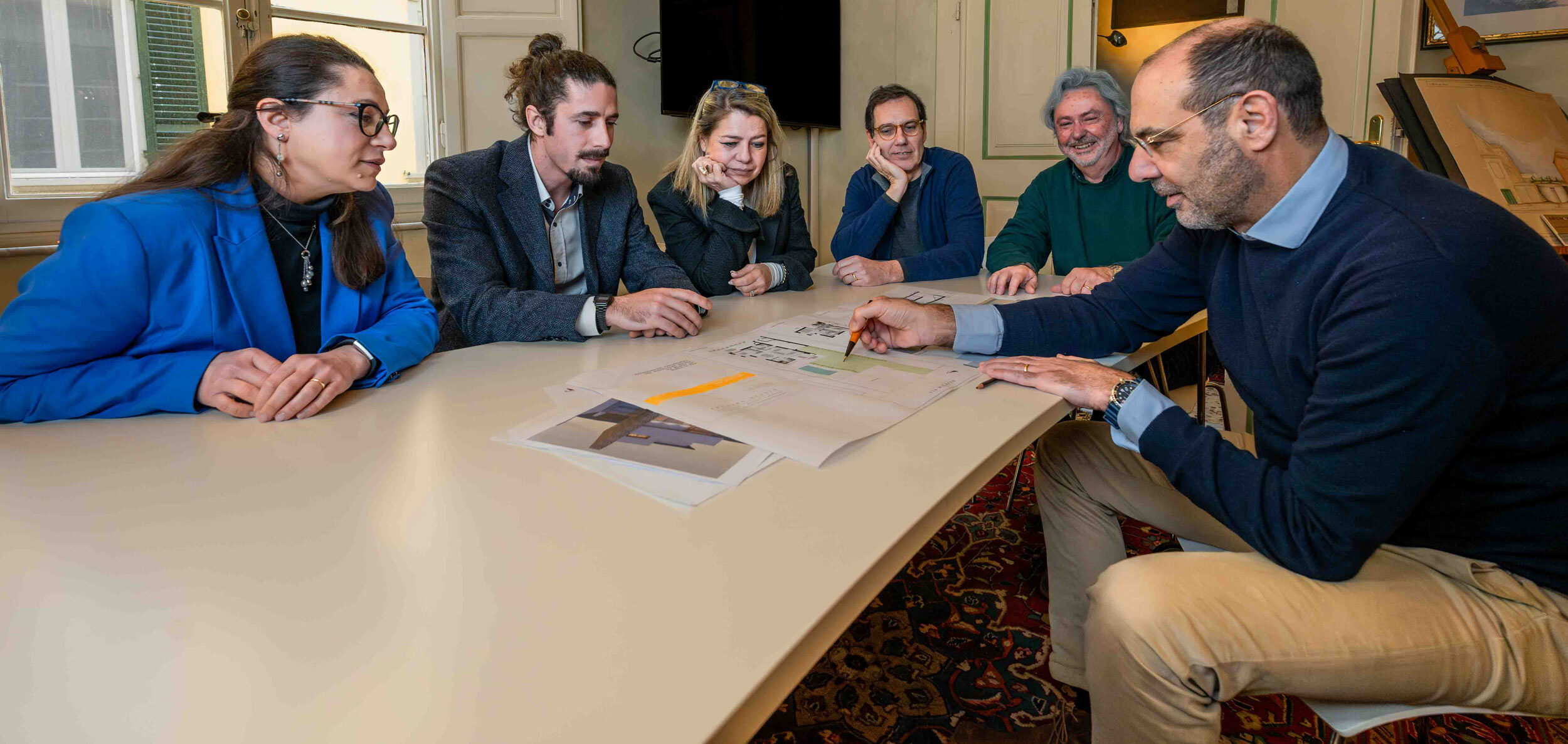 Il gruppo di Arching Studio riunito al tavolo con i disegni di progetto